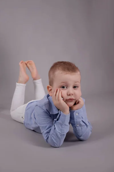 Předškolní Blondýny Chlapec Bílých Kalhotách Modré Košili Šedém Pozadí Dítě — Stock fotografie