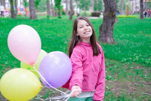 ピンクの10代のブルネットの女の子の間にカラフルな熱気球を屋外で保持している パーティー 誕生日のコンセプト 幸せな子供たち 休日や夏休み — ストック写真