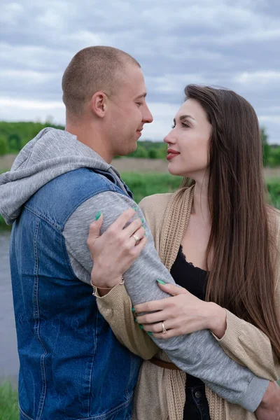 happy young couple outdoors near lake and green grass. bald man and brunette woman. husband and wife. millennials. successful marriage. true love.