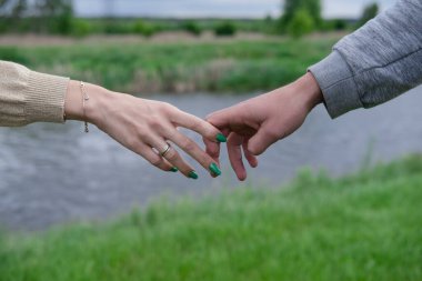 Kadın ve erkeğin elleri birbirine uzanıyor. Doğanın arka planına yumuşak ve nazik dokunuşlar. El ele tutuşun. Aşk kavramı, bağlantı, yardım, ilişki, topluluk, birliktelik, sembolizm.