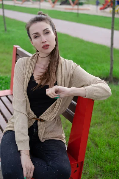 Портрет брюнетки с понирейлом, сидящей на скамейке в парке. любители природы, привлекательная девушка. — стоковое фото