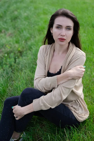 푸른 잔디 위에 앉아 있는 아름다운 갈색 머리 여인 — 스톡 사진