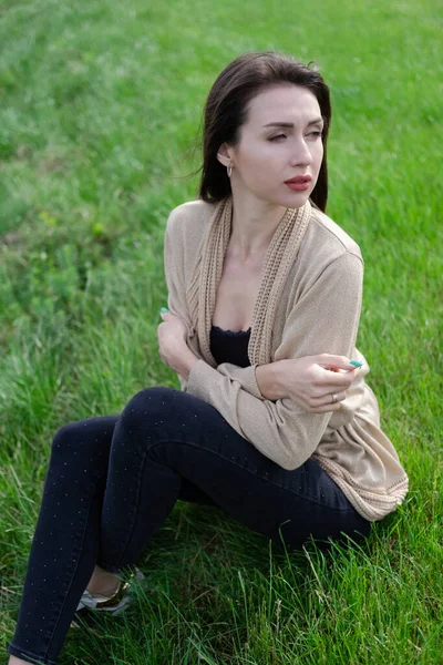 Bela mulher morena sentado na grama verde — Fotografia de Stock