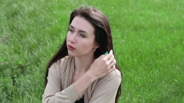 Belle femme brune assise sur l'herbe verte — Video