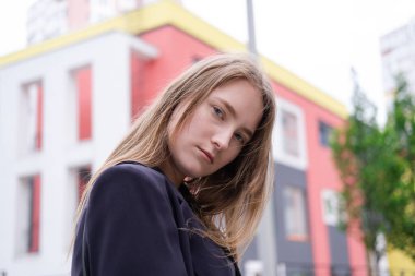 Renkli parlak binaların arka planında siyahlı çekici esmer kadının portresi. İş kadını. Kadınsı. Milenyum halkı.