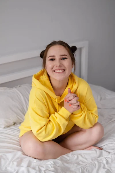 Sarı Kapüşonlu Mutlu Esmer Kız Beyaz Yatak Odasında Beyaz Çarşaflarla — Stok fotoğraf