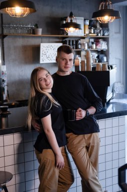 Tıpatıp aynı kıyafetleri giyen mutlu evli bir çift modern kahve dükkanında kafe sahipleri ya da işçiler gibi görünüyor. Aile işi. Çatı katı kafe