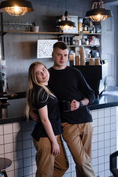 Tıpatıp aynı kıyafetleri giyen mutlu evli bir çift modern kahve dükkanında kafe sahipleri ya da işçiler gibi görünüyor. Aile işi. Çatı katı kafe