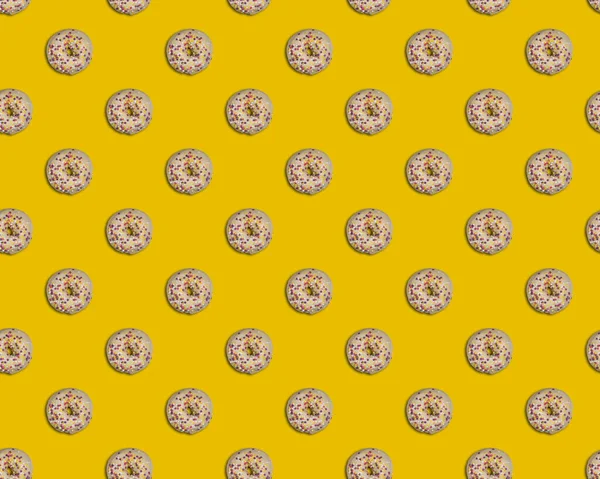 无缝隙图案 圆圆的圆圆的甜甜圈美丽的釉面与白色巧克力和五彩斑斓的黄色 粉红色和白色装饰明亮的黄色背景 从正上方看 — 图库照片