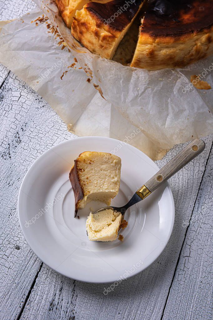 Porción picada de pastel de queso quemado vasco en un plato blanco con