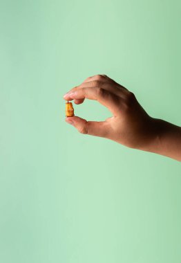 Parmaklarında küçük bir bacağı olan beyaz bir çocuk eli. Ergenlerin elinde meyve artıkları. Uzayı kopyala Tanımlanamayan kişi. Dikey oryantasyon. Sağlıklı beslenme konsepti. Yeşil nane arkaplanı.