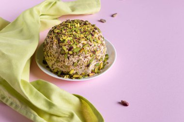 Fıstıklı susam halkası, birkaç dağınık fındık ve pembe kağıt üzerinde yeşil keten peçete. Yatay oryantasyon. Uzayı kopyala Geleneksel Orta Doğu tatlıları. Yahudi, Türk, Arap ulusal tatlısı.