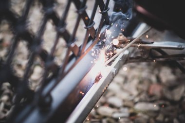 Kaynakçı, otomatik geçit operatörünü kurmadan önce çelik dişli rafı kapıdan kapıya kaynaklıyor. Otomatik kantilever kaydırma kapısının kurulumu ve bakımı için profesyonel hizmet.