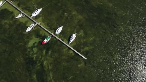 海の木製の桟橋近くの多くのボートの空中ドローンビュー — ストック動画