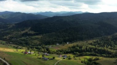 Yamaçtaki küçük, samimi bir köy. Güzel bir panoramik manzara. Dağlar kozalaklı ormanlarla kaplı, dağların yamaçlarında yeşil çimenler, temiz oksijen zengini hava. Bulutlu gökyüzü. Yaz zamanı. Ukrayna Karpat Dağları
