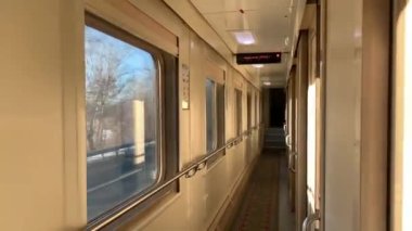 Trenin kompartıman vagonunun koridorunda, pencerenin dışında parlayan kış manzarası.