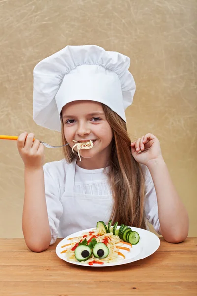 Happy little chef eating a pasta dish — Stock Photo, Image