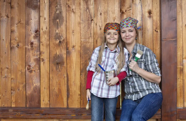 Kleines Mädchen hilft Mutter beim Streichen des Holzschuppens — Stockfoto