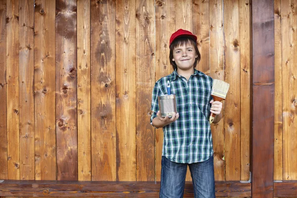 Boy painting wooden wall