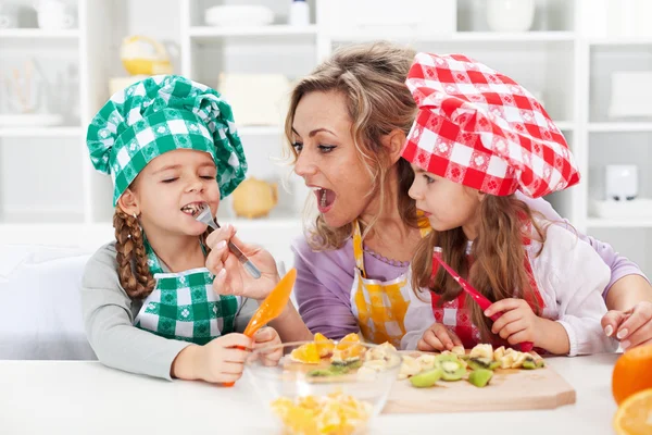 Woman and little girls preparing a fruit salad — Stock Photo, Image