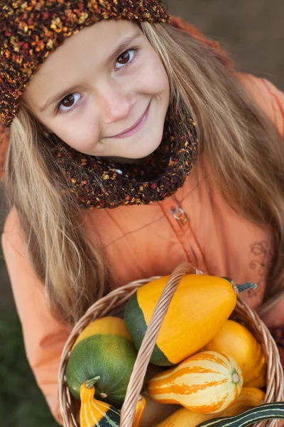 Liten flicka med en korg av pumpor — Stockfoto