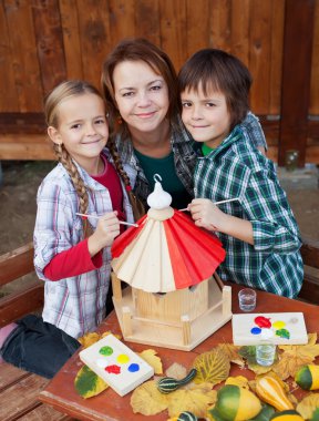 Kadın ve çocuklar bir kuş evi sonbaharda hazırlanıyor