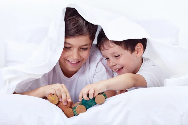 Niños jugando en la cama con juguetes de madera — Foto de Stock