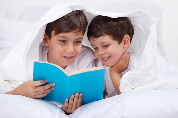 Niños leyendo debajo de la manta —  Fotos de Stock