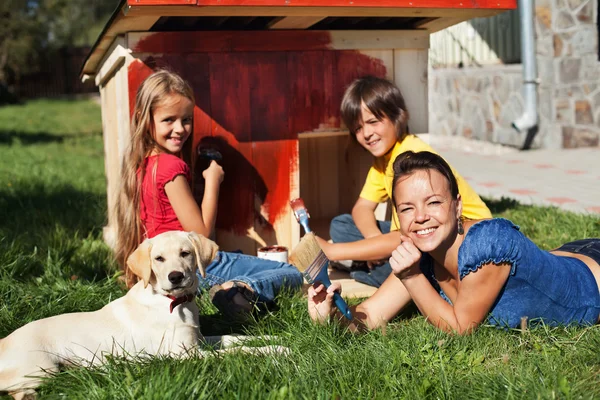 Família feliz construindo uma casa de cachorro juntos — Fotografia de Stock