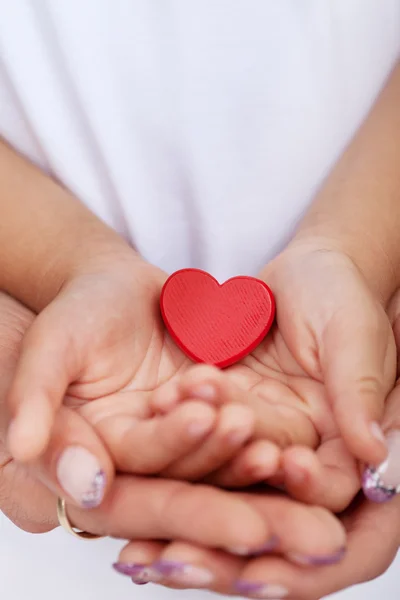 Παιδιού και ενήλικα χέρια που κρατούν την κόκκινη καρδιά — Φωτογραφία Αρχείου