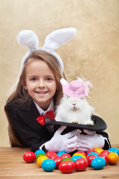 Happy magician girl holding cute bunny in magic hat — Stock Photo, Image