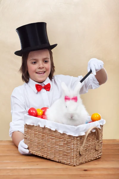 Menino mágico feliz conjurando um coelho de Páscoa e ovos coloridos — Fotografia de Stock