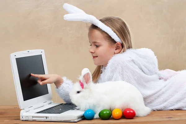 Девочка со своим кроликом за компьютером — стоковое фото