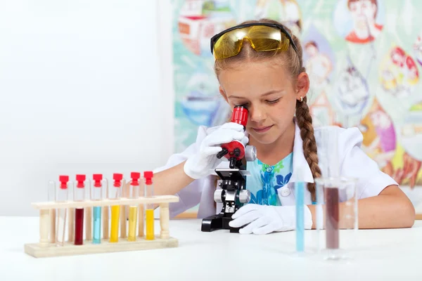 Menina na aula de ciências usando microscópio — Fotografia de Stock