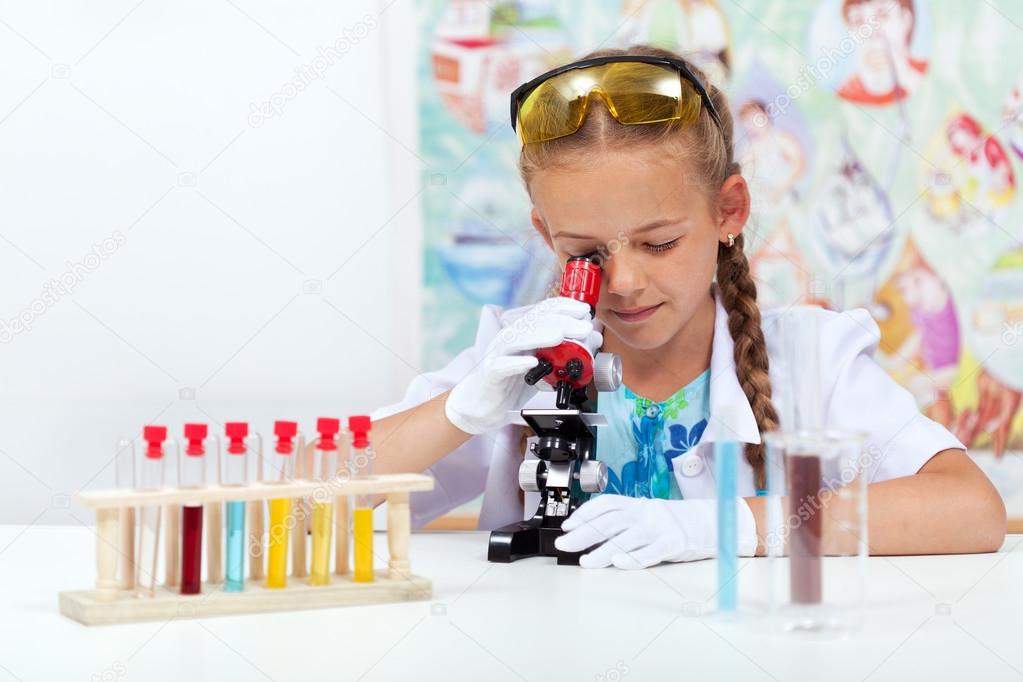Little girl in science class using microscope