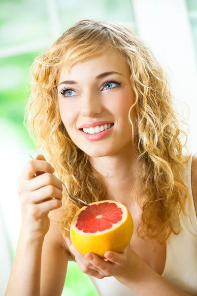 Jonge vrouw met grapefruit thuis — Stockfoto