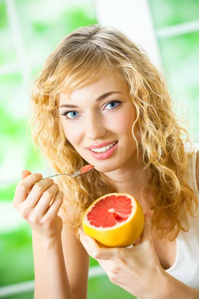 Jonge vrouw met grapefruit thuis — Stockfoto