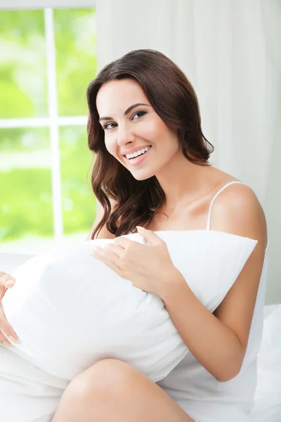 Jovem bela mulher sorridente acordando com travesseiro, no quarto — Fotografia de Stock