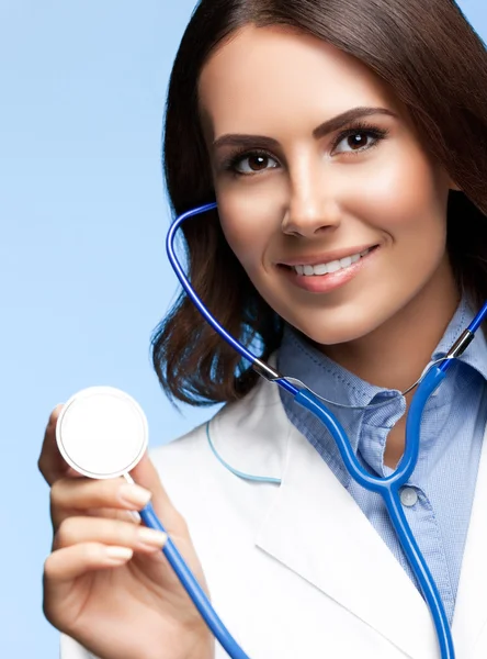 Médecin avec stéthoscope à la main, sur bleu — Photo