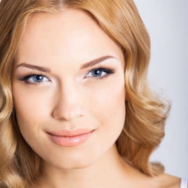 Genç neşeli gülümseyen kadın, gri 