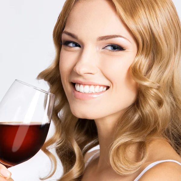 Νεαρή γυναίκα ευτυχισμένη με ποτήρι κόκκινο κρασί, σε γκρι — Φωτογραφία Αρχείου