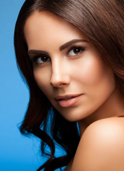 Portrait of beautiful young woman with naked shoulders, on blue — Stock Photo, Image