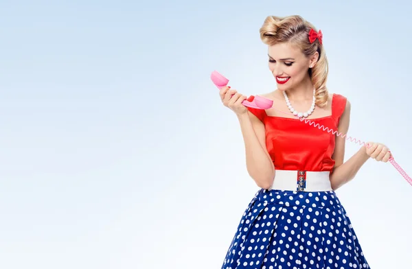 Vrouw met telefoon smiling, gekleed in pin-up stijl jurk — Stockfoto