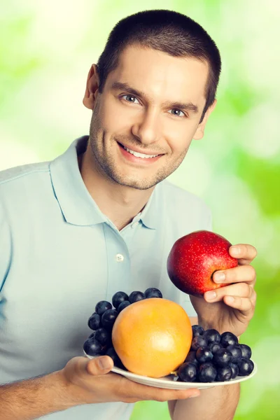 Felice uomo sorridente con piatto di frutta, all'aperto — Foto Stock