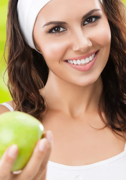 Giovane donna sorridente in abbigliamento sportivo con mela verde, outdoor — Foto Stock