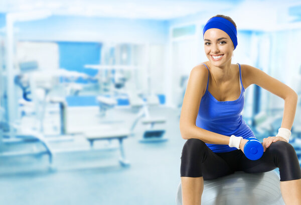 Young happy woman doing fitness exercise, at gym