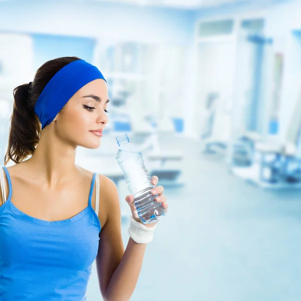 Жінка в спортивному одязі питна вода, в спортзалі — стокове фото