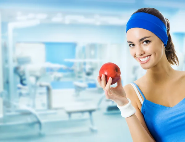 Woman in sportswear with apple, at gym — Stock Photo, Image