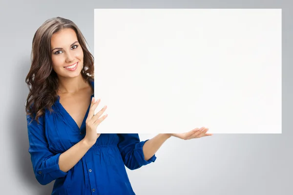 Joven mujer sonriente feliz mostrando letrero en blanco, en gris —  Fotos de Stock