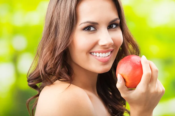 Giovane donna felice sorridente con mela, all'aperto — Foto Stock